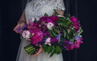 bride holding a vibrant pageant style bouquet of magenta and purple flowers