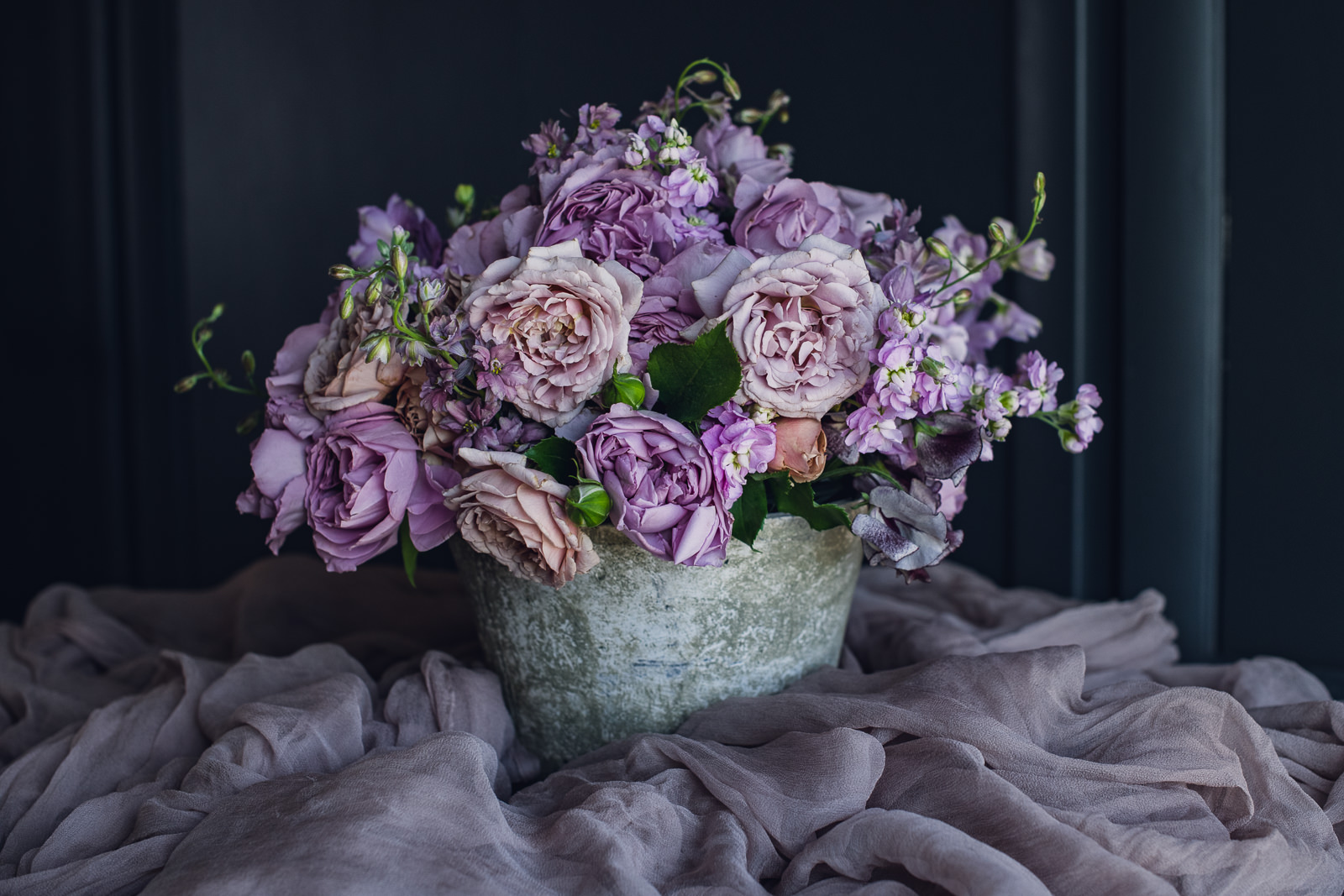 pink, purple and blush centerpiece in a grey ceramic container in a pile of fig color silk
